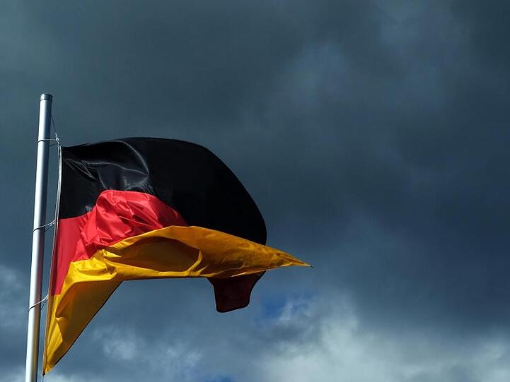 Eine Deutschlandfahne vor dunklen Wolken.