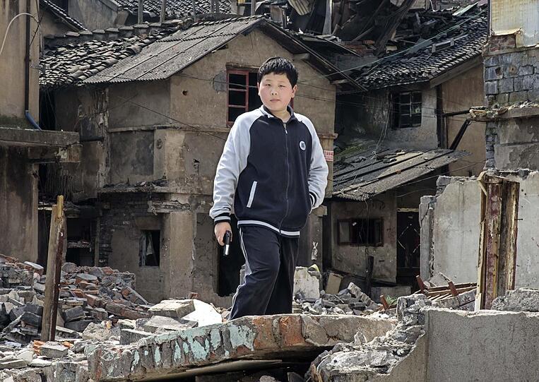 "Mit großer Spannung und Anteilnahme verfolgte ich die weitere Entwicklung des Viertels in unmittelbarer Nachbarschaft zum Ort meiner Kindheit. Bei meinen letzten Besuch im Frühjahr 2013 in Shanghai waren bereits über 100 Behausungen der Bewohner abgerissen. Beim Studieren der Ruinen und Wohnungen, die nun ihr Inneres nach außen gekehrt haben, beobachtete ich ein paar Jungen beim Guerilla-Spiel. Heute spielen sie vielleicht nur die Rolle der Rebellen, um Freiheit, Selbstbestimmung und Gerechtigkeit herzustellen; und morgen?"