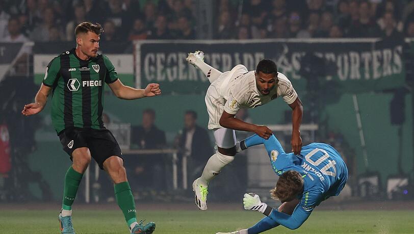 Münsters Torwart Johannes Schenk (r) im Kampf um den Ball mit Münchens Serge Gnabry (M), der sich dabei verletzt.