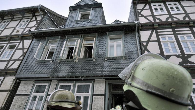 Einsatzkräfte der Feuerwehr blicken auf das ausgebrannte Haus.