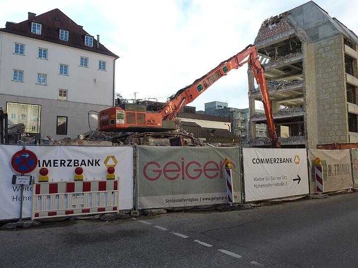Der riesige Arm des Baggers hebt Bauschutt am Boden auf.
