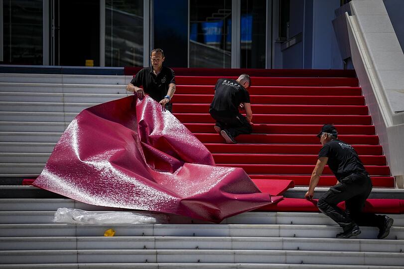 Mitarbeiter legen den roten Teppich am Palais de Festival für das 77. internationale Filmfestival in Cannes aus.