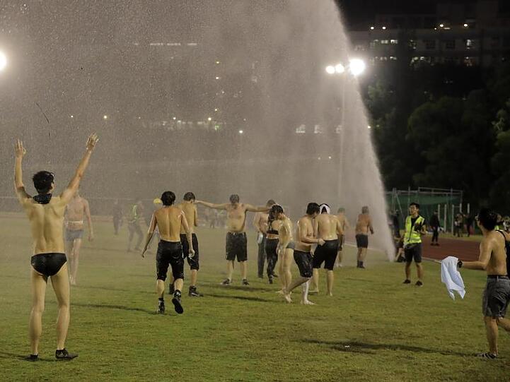 Studenten stehen bei Zusammenstößen mit der Polizei an der Chinese University unter dem Strahl eines Wasserwerfers.