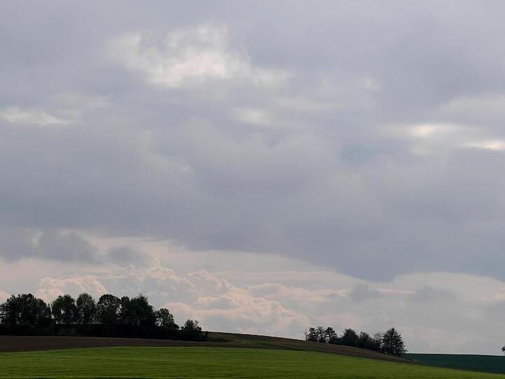 Dunkle Wolken ziehen über Felder. Foto: Angelika Warmuth/dpa/Archivbild