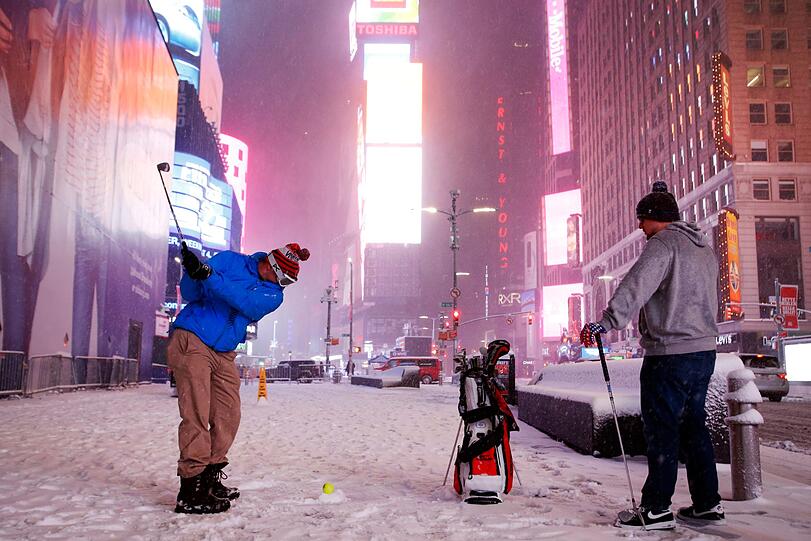 14.03.2017: Wintersport mal anders: Zwei Männer spielen mit einem Tennisball Golf auf dem verschneiten Times Square in New York.