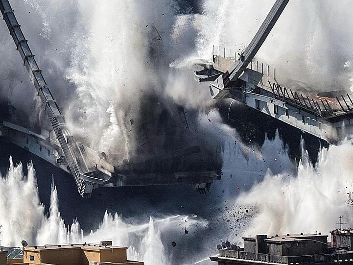 In einer gigantischen Staubwolke sacken die restlichen Pfeiler der Morandi-Brücke in Genua bei einer geplanten Explosion in sich zusammen.