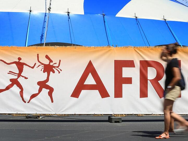 Besucher des Africa-Festivals gehen vor dem Logo des Festivals entlang. Foto: Karl-Josef Hildenbrand/dpa/Archivbild