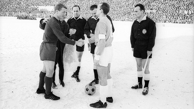 8. Januar 1966: In seiner ersten Bundesliga-Saison liefert sich der FC Bayern ein heißes Rennen mit dem Lokalrivalen TSV 1860. Und gewinnt beim Start in die Rückrunde mit 3:0 (0:0) im Grünwalder Stadion. Hier sehen wir die beiden Kapitäne Werner Olk und Peter Grosser (TSV 1860) bei der Platzwahl.