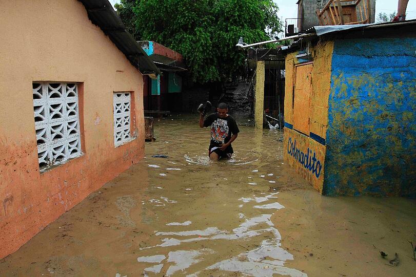 Nur ein paar Wertgegenstände trägt dieser Mann bei sich, als er durch die Fluten in San Cristobal watet.