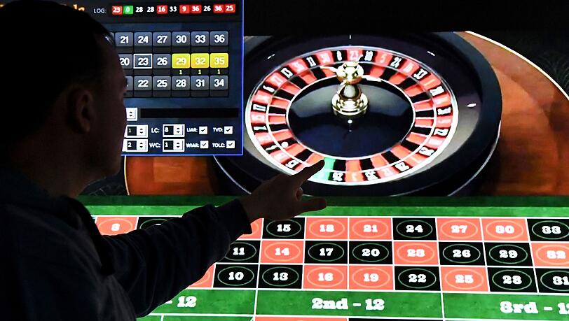 Ein Mann steht vor einem Bildschirm mit einer Seite für Online-Roulette.