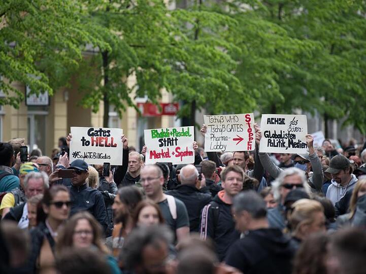 Demonstranten halten bei der Kungebung in Berlin Schilder hoch, auf denen sie unter anderem Bill Gates und die WHO angreifen.