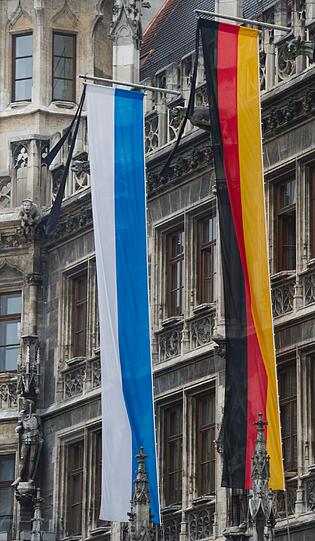 Eine bayerische und eine deutsche Fahne mit Trauerflor hängen am Mittwoch am Rathaus.