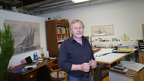 Franz Huber an seinem Schreibtisch, im Nordflügel des Deutschen Museums. Hier wird erst recherchiert und gezeichnet, wie das Modell später aussehen soll. Die Bilder an den Wänden: Ein Segelboot, das Huber täglich die Kraft der Natur vor Augen führt (l.) und der Wright Flyer (r.), eines der Lieblingsprojekte des Modellbauers.