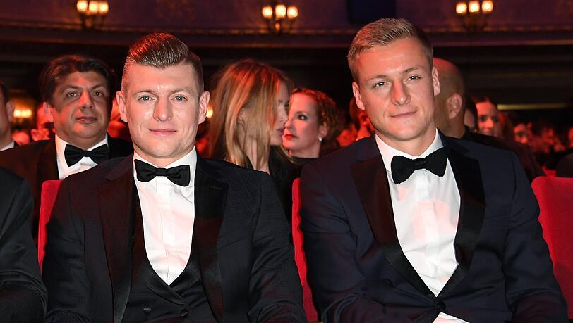 Toni Kroos (l) und sein Bruder Felix Kroos (r) sitzen bei einer Veranstaltung nebeneinander.