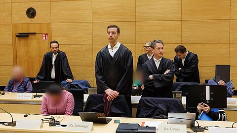 Drei der zehn Angeklagten sitzen am ersten Prozesstag im Landgericht Bielefeld neben ihren Verteidigern.