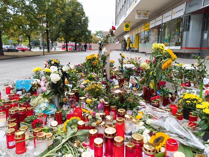 Ein Holzkreuz und ein Foto des Opfers stehen zwischen Blumen und Kerzen am Tatort.