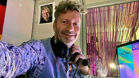 Thorsten Schorn kommentiert den ESC im Ersten - mit einem Porträt von Vorgänger Peter Urban im Hintergrund.