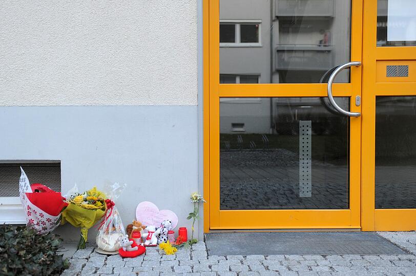 Blumen, Kerzen, Stofftiere und ein Papierherz liegen in Unterföhring vor einem Hauseingang zu Gedenken an die ermordete Larissa.