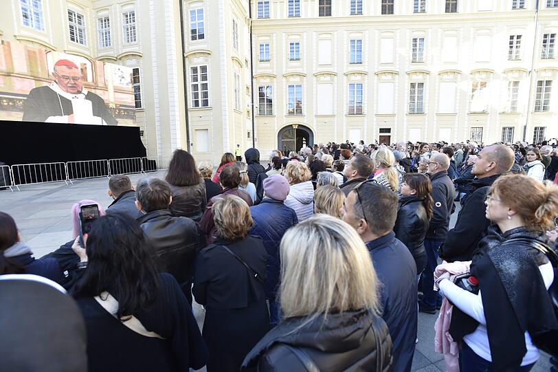 Fans schauen auf einen Großbildschirm, auf dem die Trauerfeier für den Sänger Karel Gott im Prager Veitsdom übertragen wird.