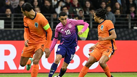 Deutschlands Jamal Musiala (M) kämpft gegen Nathan Aké aus den Niederlanden () und Virgil van Dijk um den Ball.
