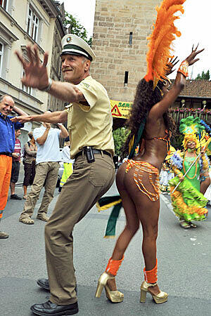 Da kann selbst ein Polizist, wie hier beim 17. Samba-Festival in Coburg (Oberfranken), nicht widerstehen und lässt sich von einer brasilianischen Tänzerin zum Tanzen verführen