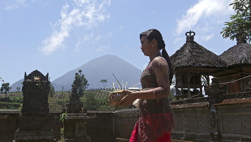 Ein Balinesin bringt Opfergaben in einen Tempel der 10 Kilometer vom Vulkan Mount Agung entfernt liegt. Ein Balinesin bringt Opfergaben in einen Tempel der 10 Kilometer vom Vulkan Mount Agung entfernt liegt.