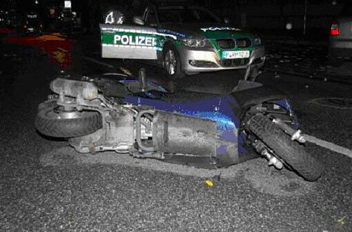 Das kaputte Motorrad liegt vor dem Polizeiauto.