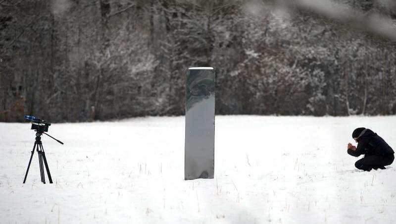Unterhalb des Schlosses Neuschwanstein auf einer Wiese im Schnee steht der Monolith aus Metall.