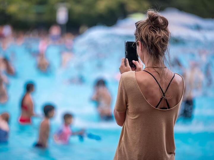Eine junge Frau fotografiert mit ihrem Handy im Prinzenbad.