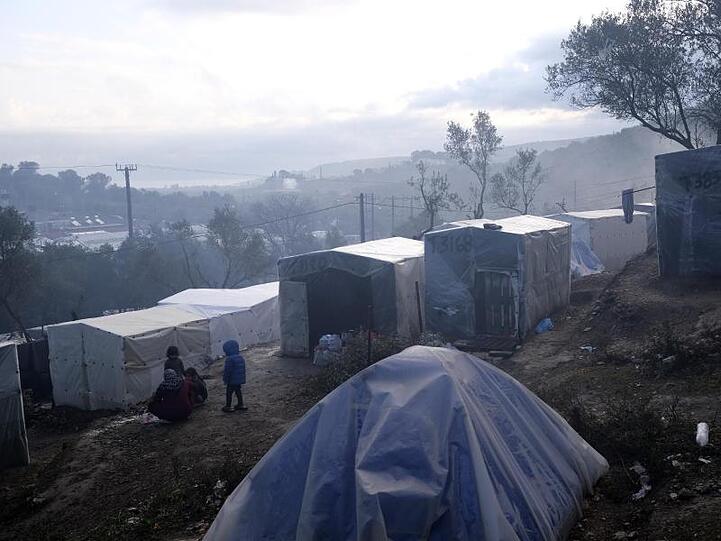 Kinder stehen nach einem Regenguss vor provisorisch errichteten Zelten außerhalb des Flüchtlingslagers Moria auf Lesbos. In und um die Registrierungslager harren mehr als 42.000 Menschen aus.