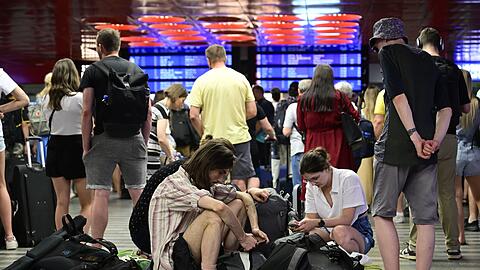 Passagiere sitzen in der Halle des Prager Hauptbahnhofs während eines Stromausfalls.