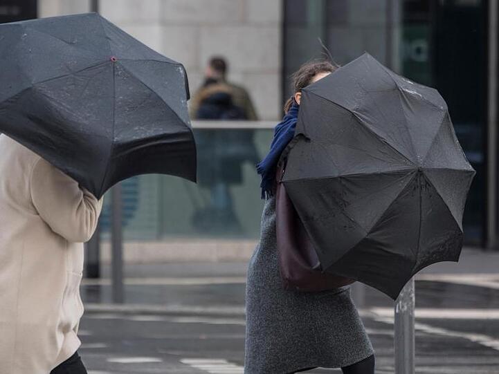 Eine heftige Sturmböe erfasst die Schirme von zwei Passantinnen. Foto: Boris Roessler/dpa/Archivbild