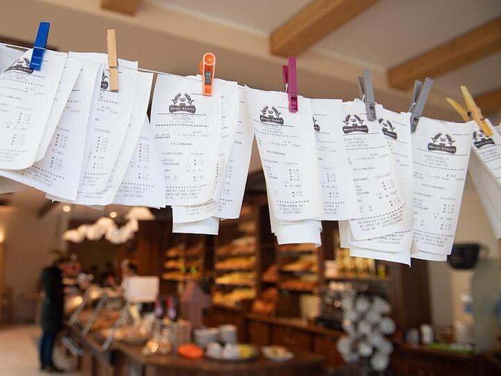 Zahlreiche Kassenzettel hängen in einer Bäckerei an einer Leine.