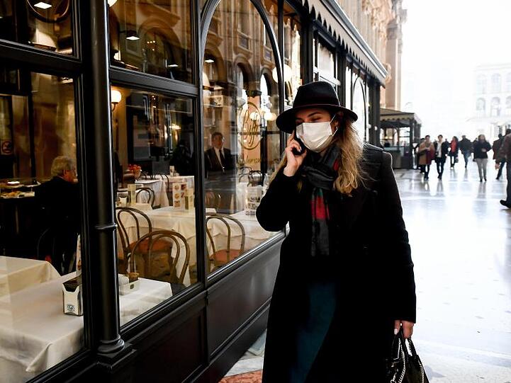 Eine Frau mit Mundschutz vor einem Restaurant in Mailand.