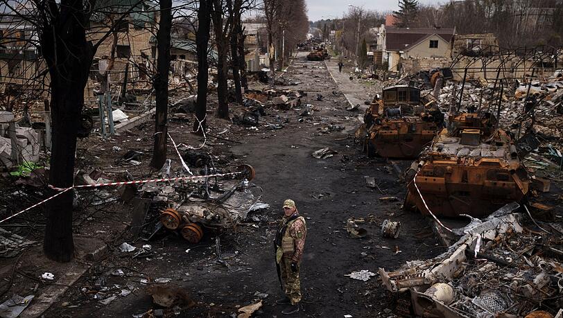 Ein ukrainischer Soldat steht in Butscha neben zerstörten russischen Panzern. Ein ukrainischer Soldat steht in Butscha neben zerstörten russischen Panzern.