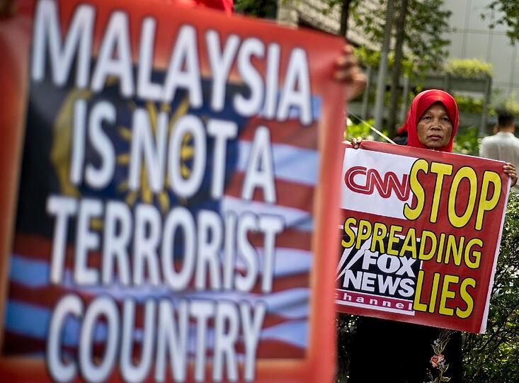 Malaysische Aktivisten halten während eines Protestes Plakate, auf denen sie den US-Kanälen unprofessionelle Berichte über den verschollenen Malaysia Airlines Flug vorwerfen.