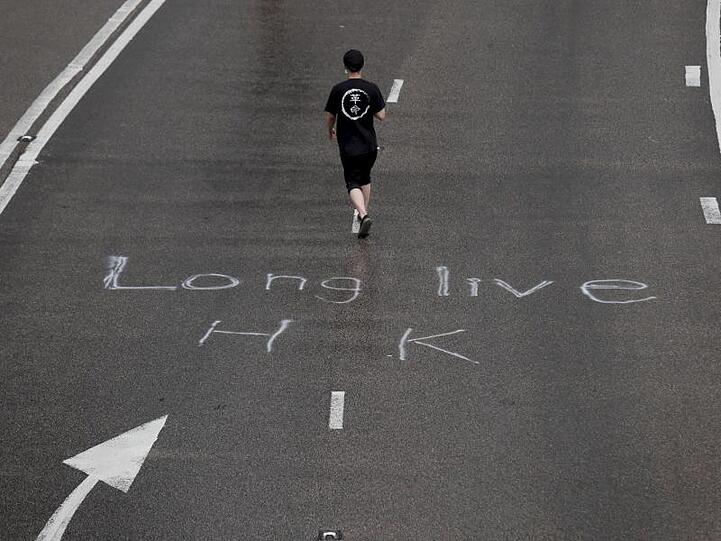 Ein Demonstrant auf einer Straße, auf der "Long live HK" (Lang lebe Hongkong) steht.