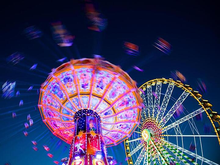 Ein Kettenkarussell dreht sich auf der Cranger Kirmes neben einem Riesenrad. Foto: Marcel Kusch/dpa/Archiv
