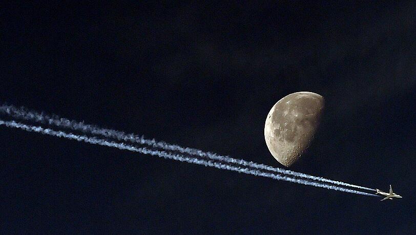 Ein Flugzeug hinterlässt einen Kondensstreifen, während es aus Sicht des Fotografen den Mond passiert. Das Bild wurde in der algerischen Hauptstadt Algier aufgenommen. Ein Flugzeug hinterlässt einen Kondensstreifen, während es aus Sicht des Fotografen den Mond passiert. Das Bild wurde in der algerischen Hauptstadt Algier aufgenommen.