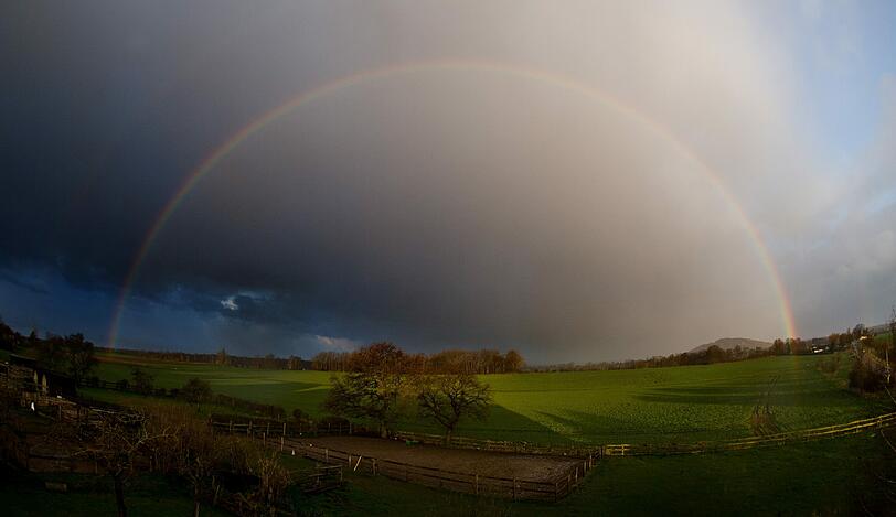 Ein Regenbogen spannt sich am 29.03.2015 bei stürmischen Wetter über Felder bei Sehnde in der Region Hannover (Niedersachsen).