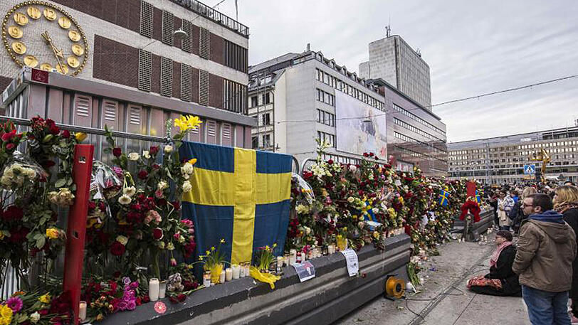 Passanten haben Blumen an einer Absperrung vor dem Stockholmer Kaufhaus AAhléns City befestigt.