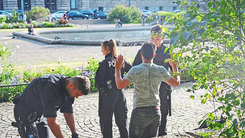 Bereitschaftspolizisten durchsuchen den Rucksack eines weiteren Verdächtigen im Park.