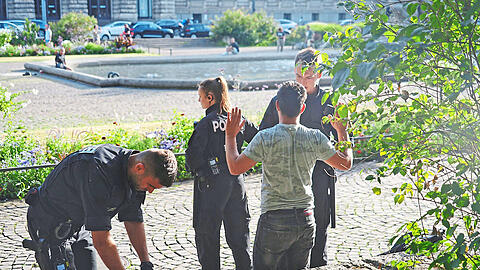 Bereitschaftspolizisten durchsuchen den Rucksack eines weiteren Verdächtigen im Park.