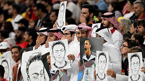 Zuschauer halten Bilder von Deutschlands ehemaligem Nationalspieler Mesut Özil in die Höhe.