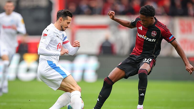 Kiel-Kapitän Steven Skrzybski (links) und Pape Demba Diop von Nürnberg kämpfen um den Ball.
