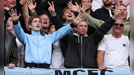 Noel Gallagher (2.v.re., schwarze Jacke) mit seinen beiden S&ouml;hnen Sonny (li., blaue Jacke) und Donovan (Mitte, verdeckt, wei&szlig;es T-Shirt) im Stadion von Manchester City.