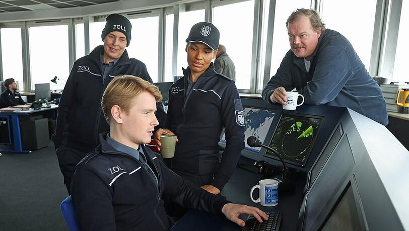 "Der Bremerhaven-Krimi. Geschäft mit dem Tod": Zöllner Sven-Erik Dröse (Lukas Zumbrock, sitzend) hat eine heiße Spur (v.l.n.r. Elena Uhlig, Cynthia Micas, Bernd Hölscher).