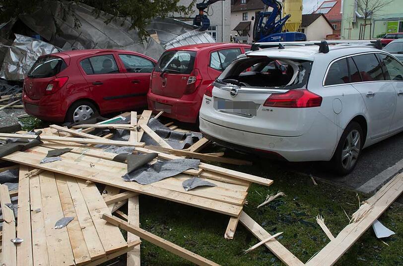 Losgelöste Dachteile liegen am 31.03.2015 in Weilheim (Bayern) auf geparkten und stark beschädigten Autos.