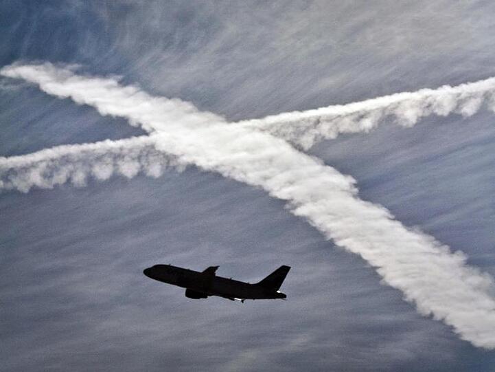 Ein Flugzeug startet vom Flughafen Frankfurt am Main vor Kondensstreifen am Himmel.