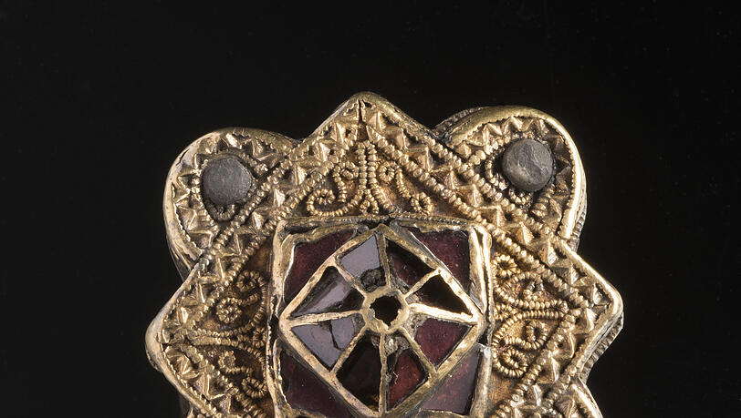 Die goldene Vierpassfibel (um 600) aus dem Frauengrab. Die goldene Vierpassfibel (um 600) aus dem Frauengrab.